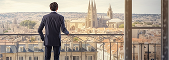 Un homme d'affaire regarde la ville d'Avignon du haut d'un balcon